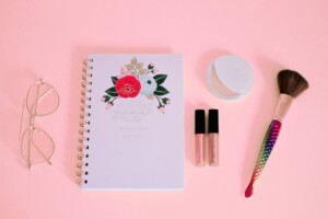 flat lay photography of notebook near eyeglasses and make up