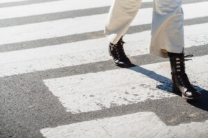 woman crossing asphalt road on zebra
